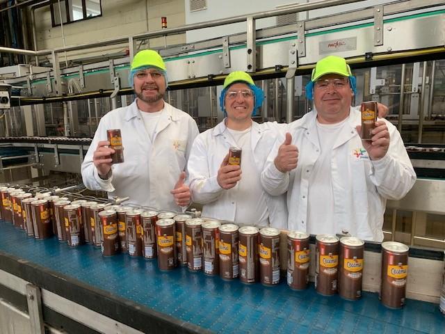 Three humans holding Chocomel cans