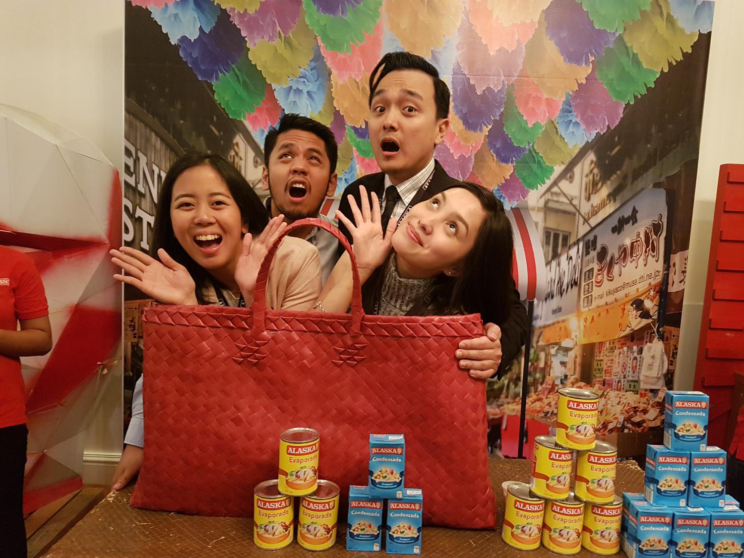 Four people posing with a large bag in front of them