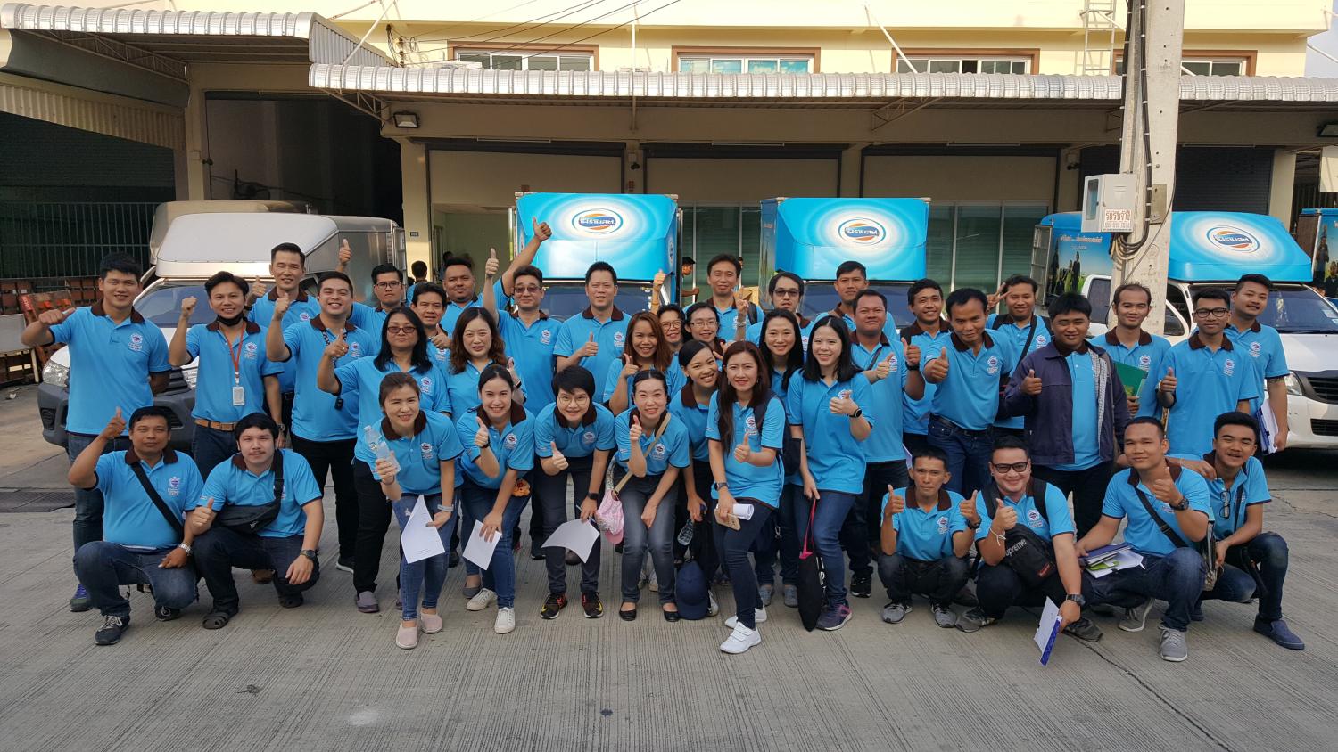 Large group of people in blue shirts posing for the camera